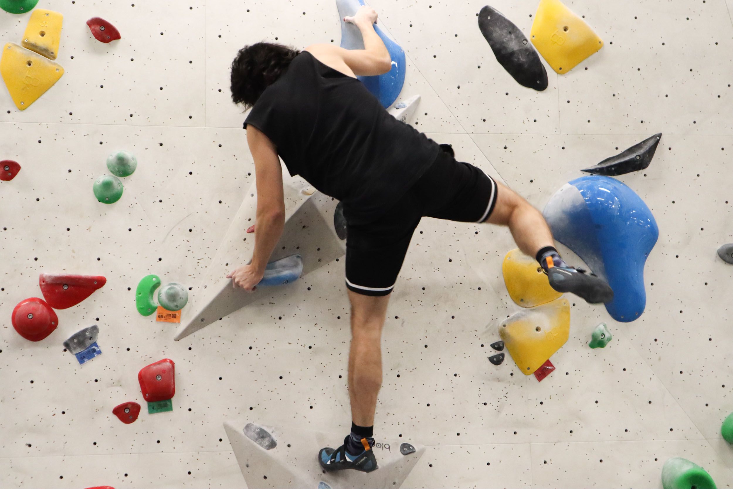 Mies kiipeilee kiipeilyseinällä