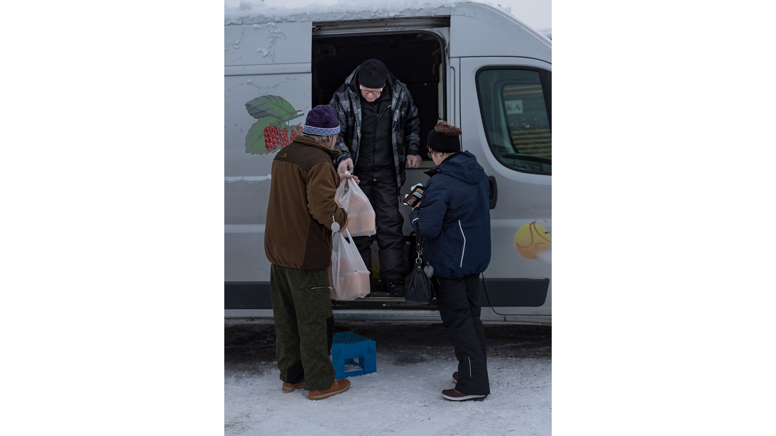 Myyjä Reijo Rukola ojentaa pakettiautostaostajille kaksi muovikassia, jossa on pakastettua ternimaitoa.