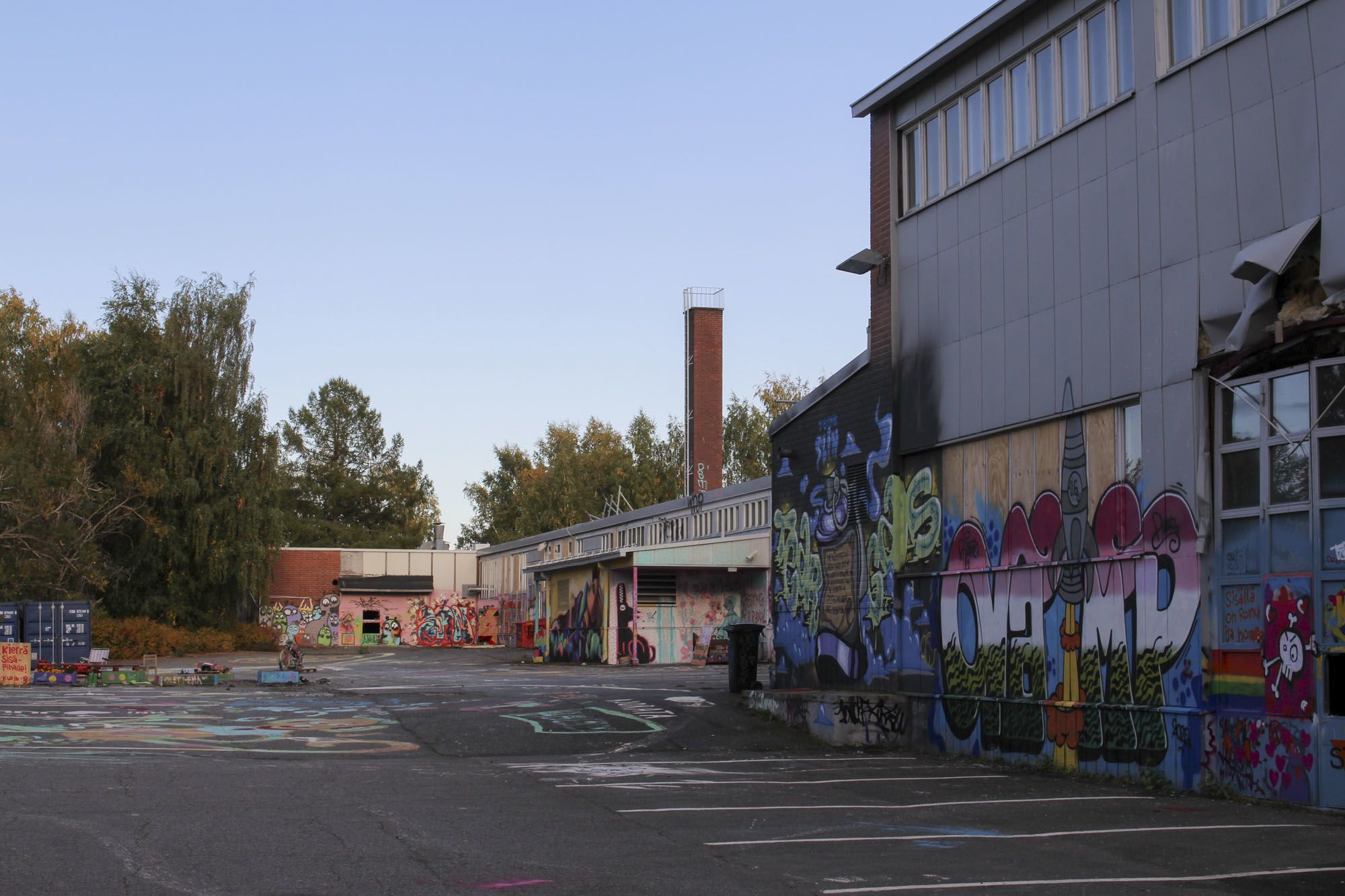 Vanhan ammattikoulun pihaa ja rakennuksia. Rakennusten ulkoseinät ovat täynnä graffitimaalauksia.
