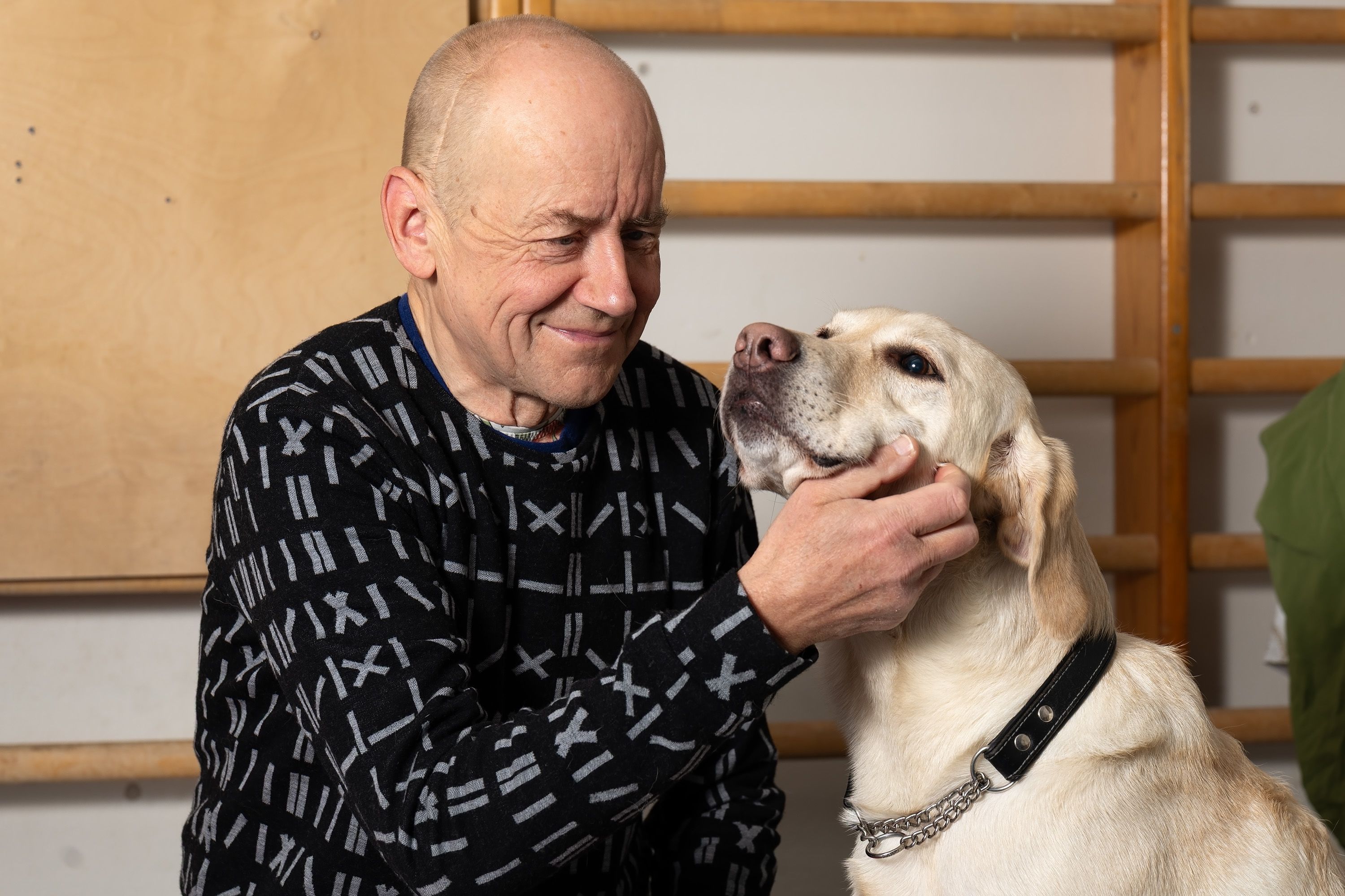 Janne Silas silittää Patu-koiraa hymyillen, Patu näyttää myös siltä kuin hymyilisi.