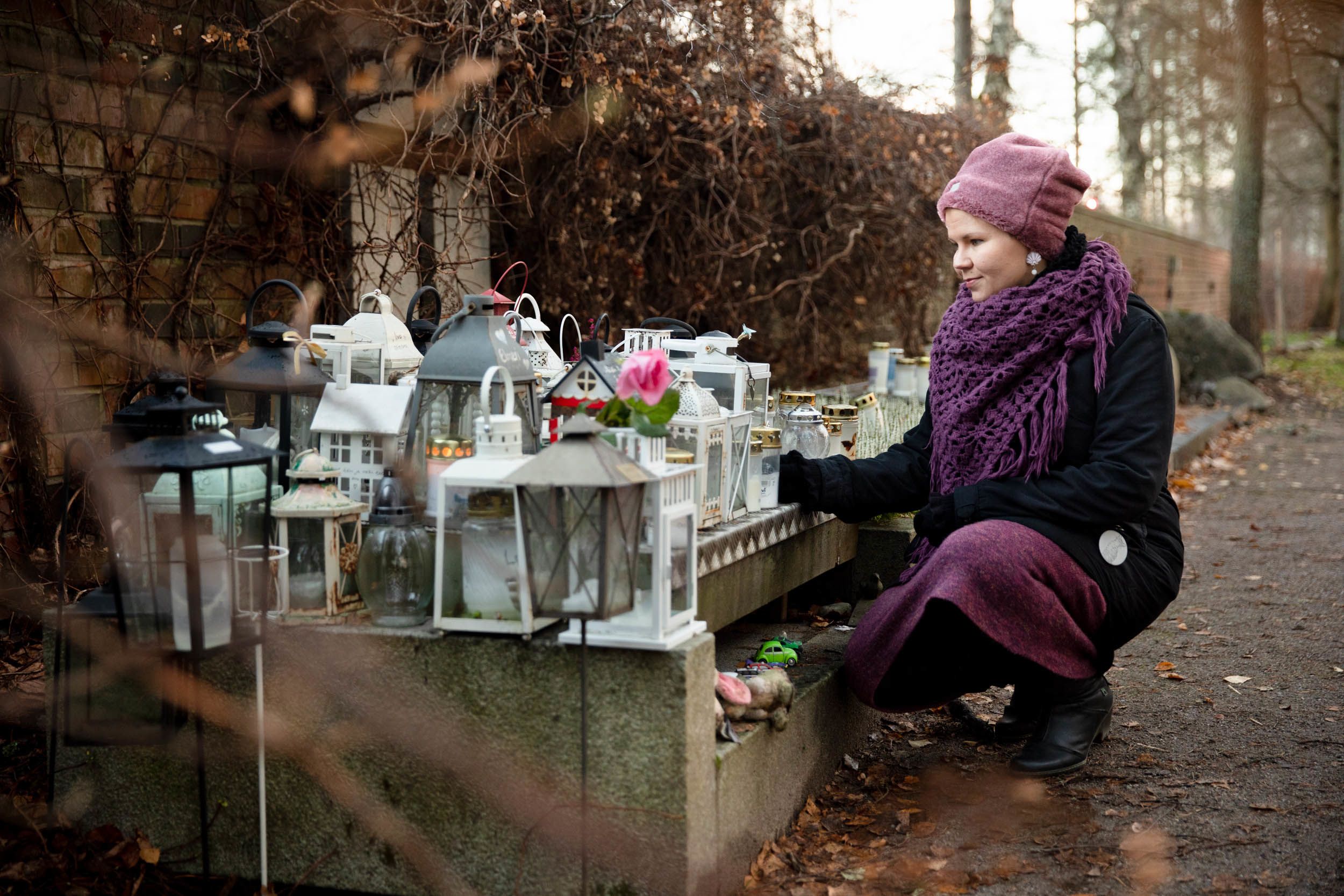 Henkilö on kyykistynyt muistelupaikan kynttilöiden äärelle.  