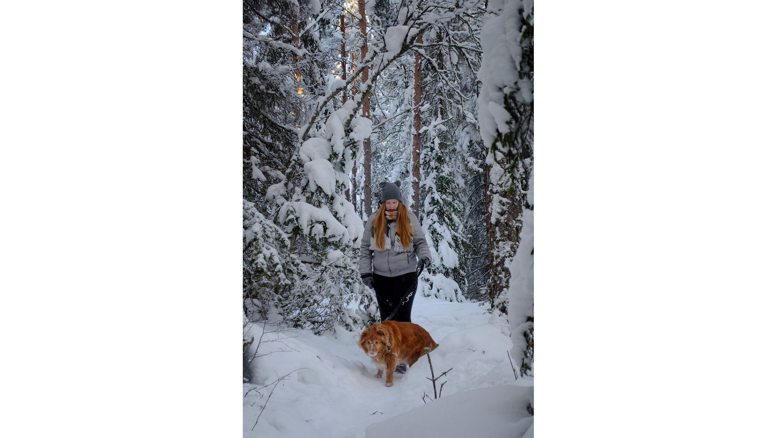 Nuori nainen metsässä koiran kanssa.