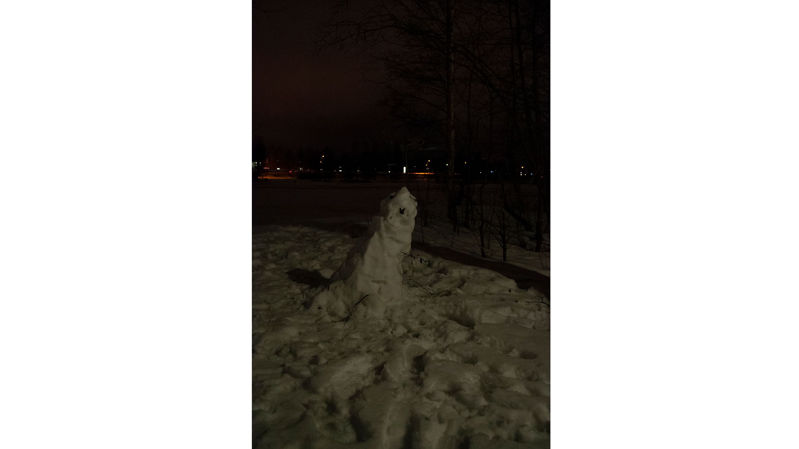 Vähän jo sulamaan alkanut lumiukko pimeällä.