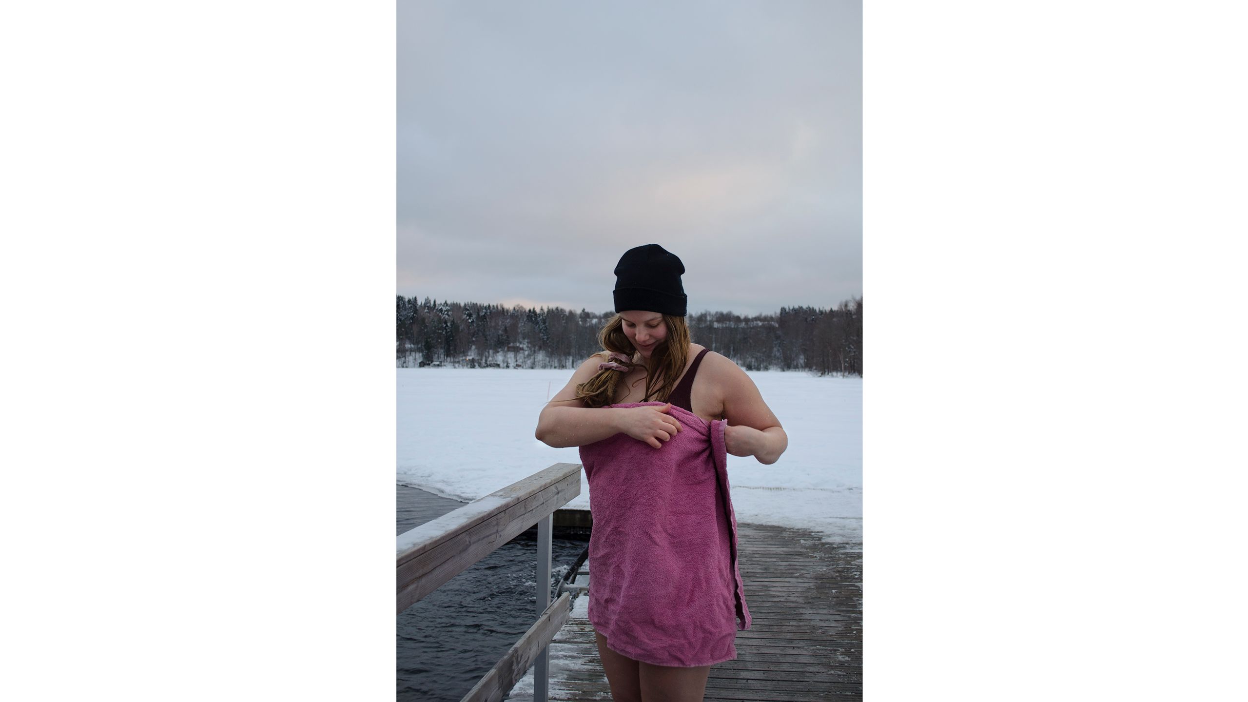 Nuori nainen laiturilla pyyhkeeseen kietoutuneena.