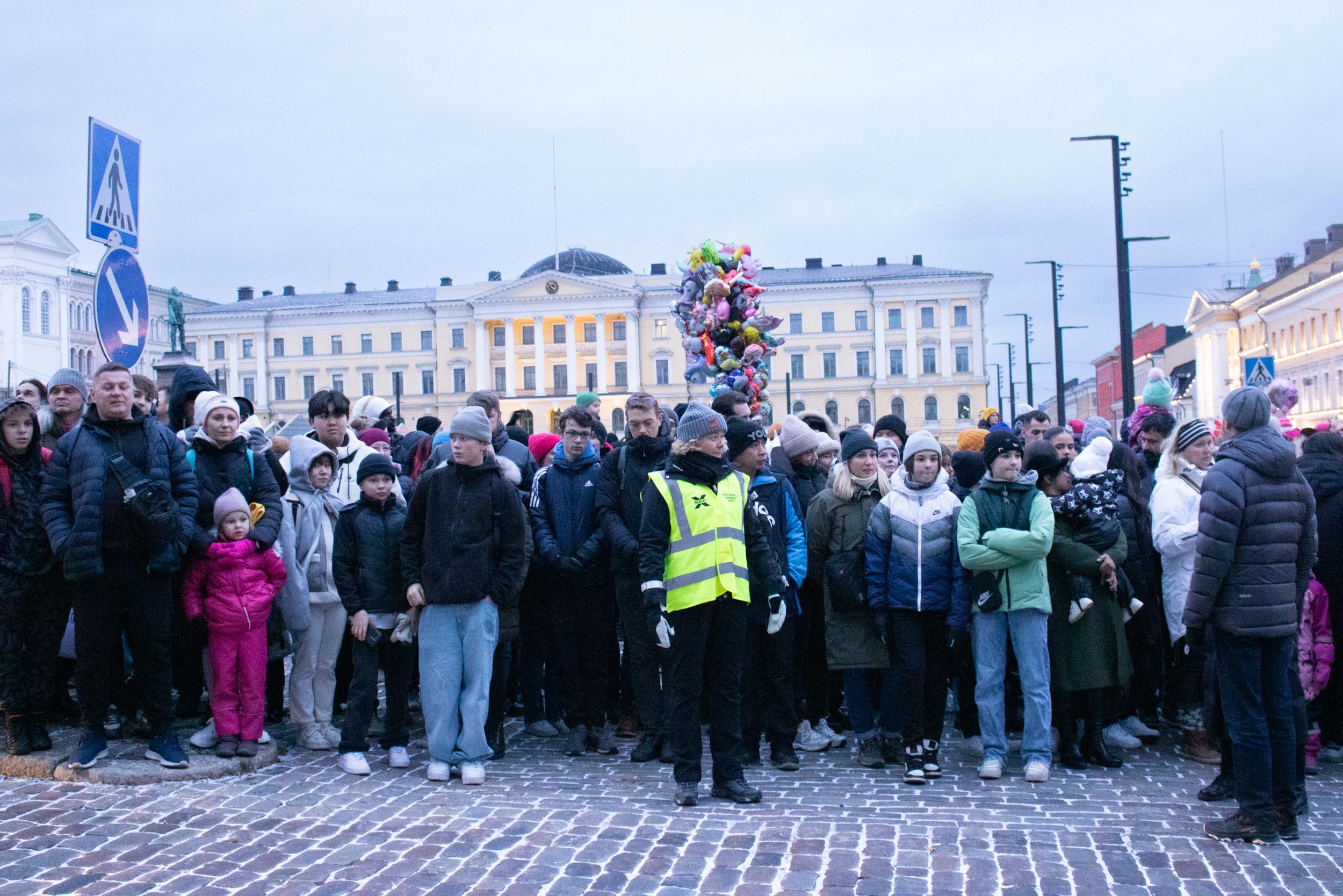 Ihmisjoukko seisoo senaatintorin reunalla odottamassa jouluparaatia.